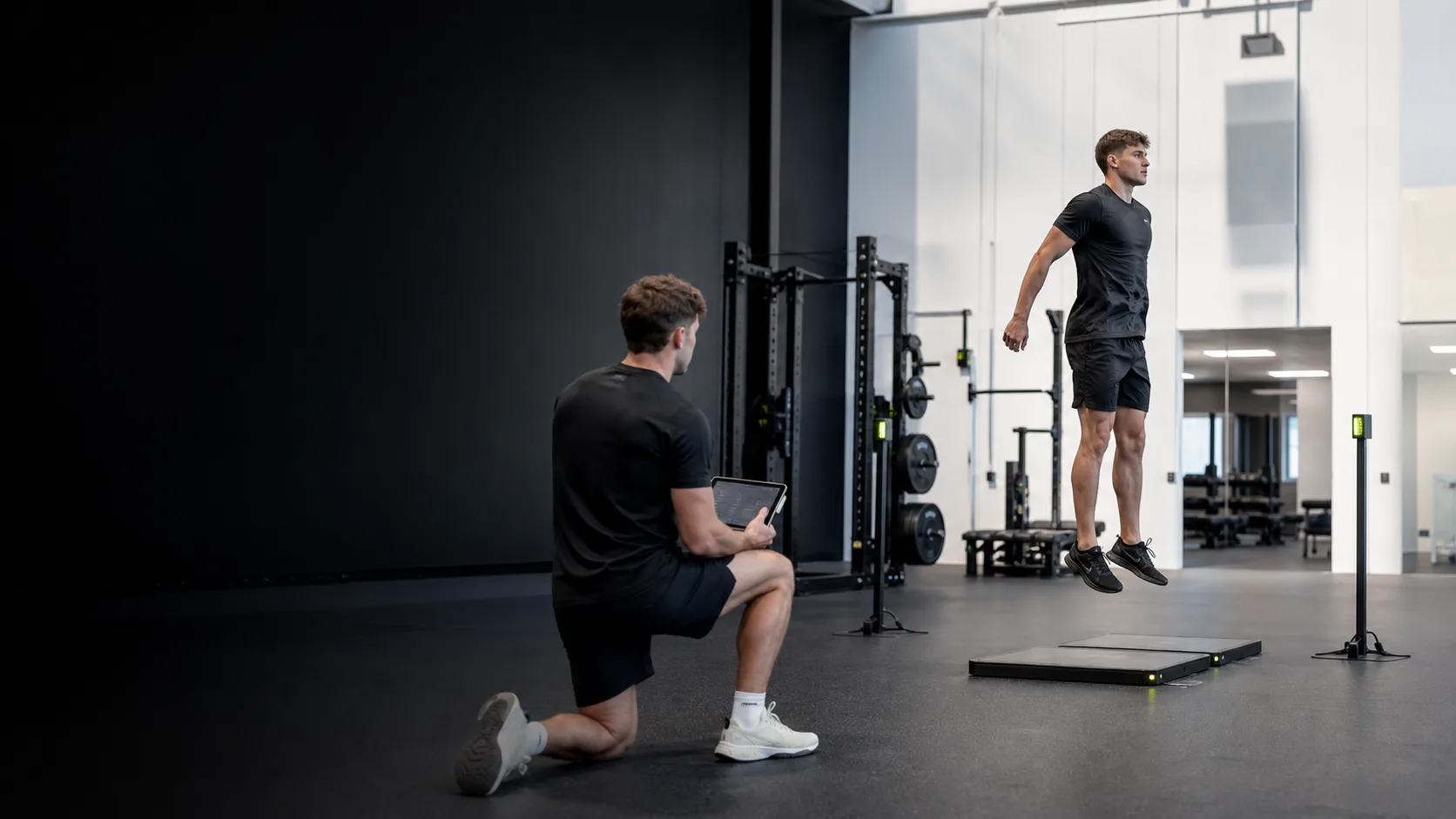 Athlete jumping on force plates while a coach reviews testing data